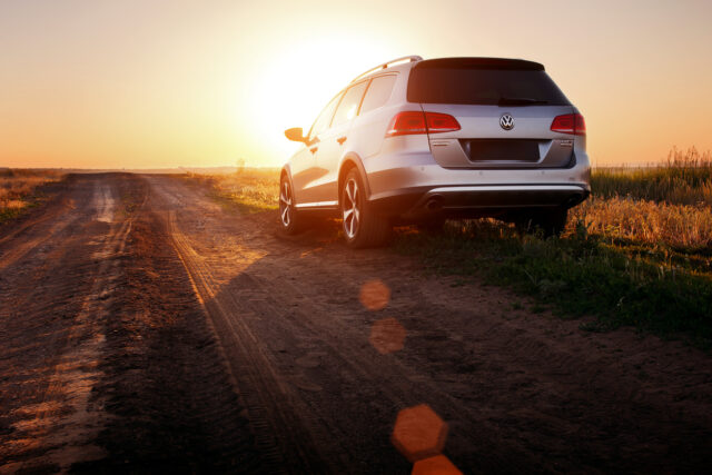 Grey car Volkswagen Passat stay on dirt road at sunset